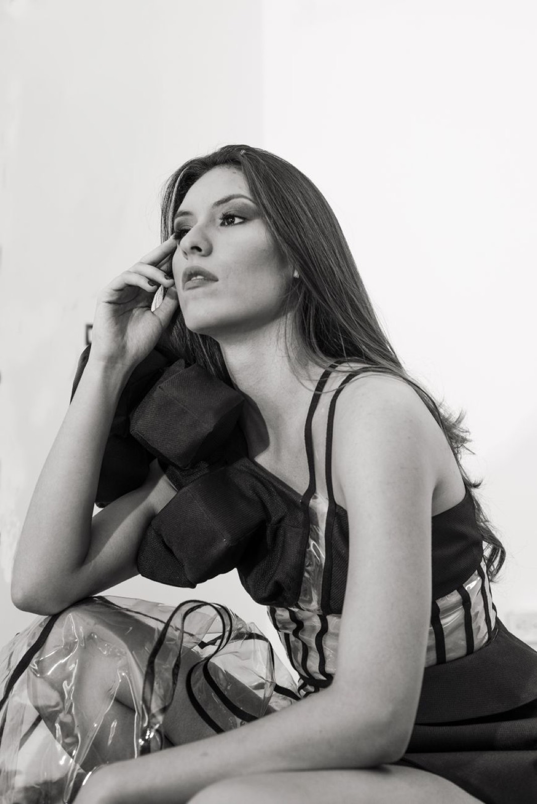 A model in black, hand to her face, photographed in black and white
