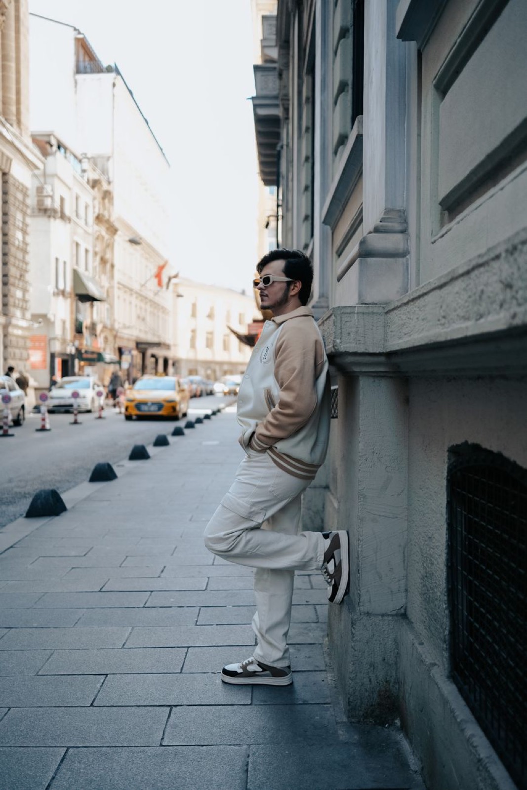 A man in cream leaning against a doorway on a city street