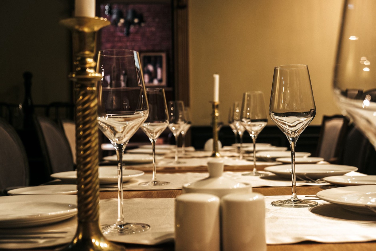 A long table set with wine glasses and a tall brass candlestick