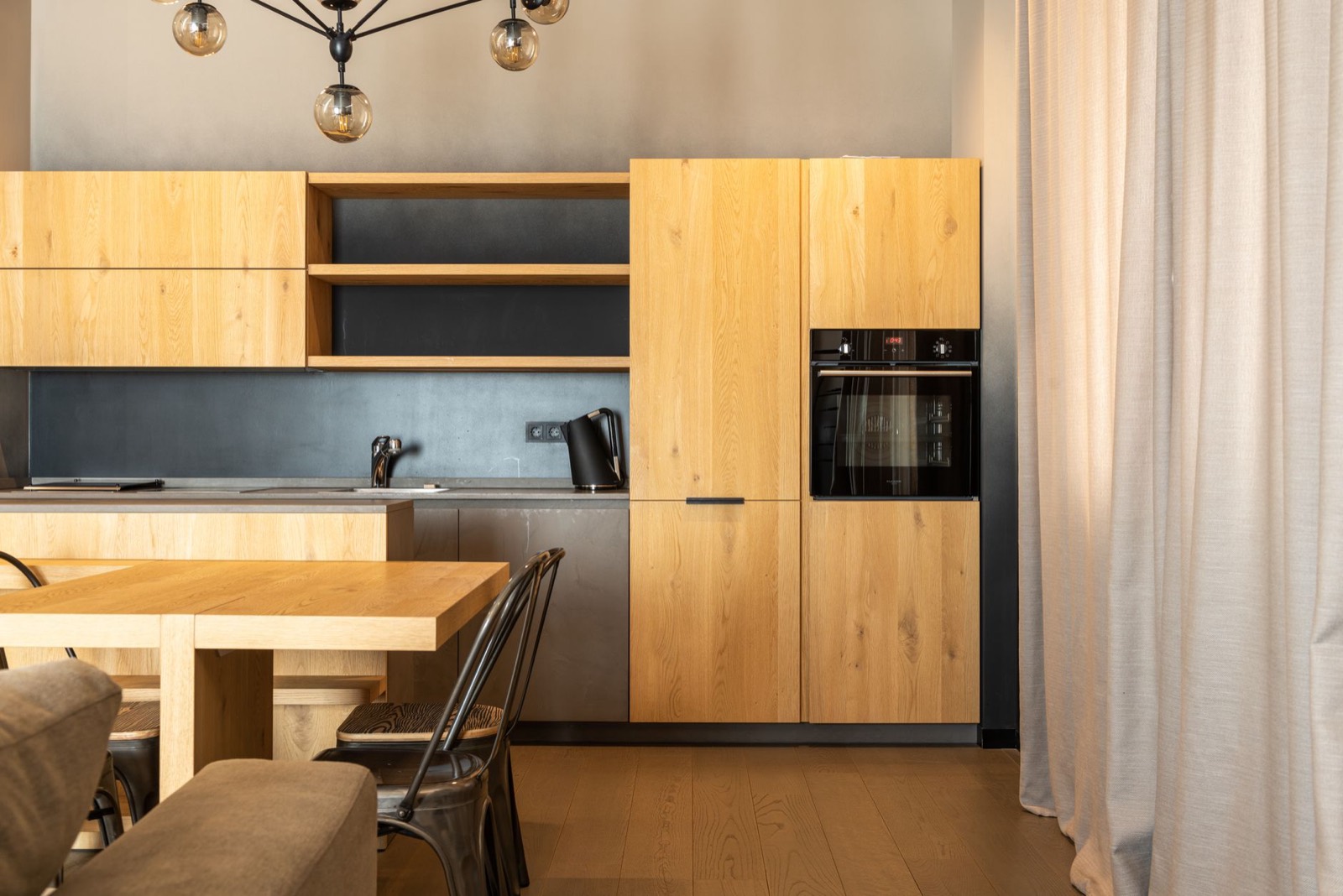 A kitchen with oak cabinets and a dark splashback