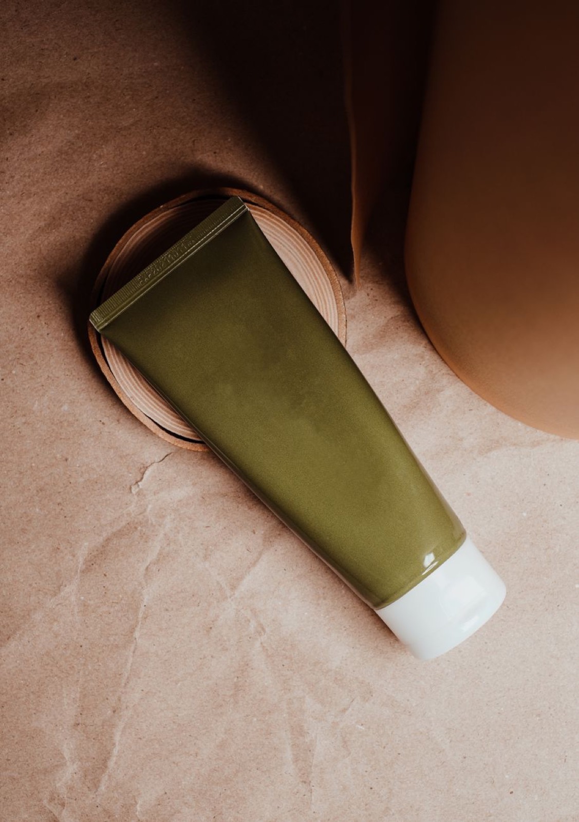 A green tube of skincare on stone