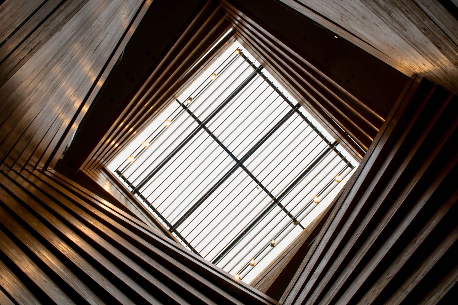 Looking up through a timber-lined atrium to a square of sky
