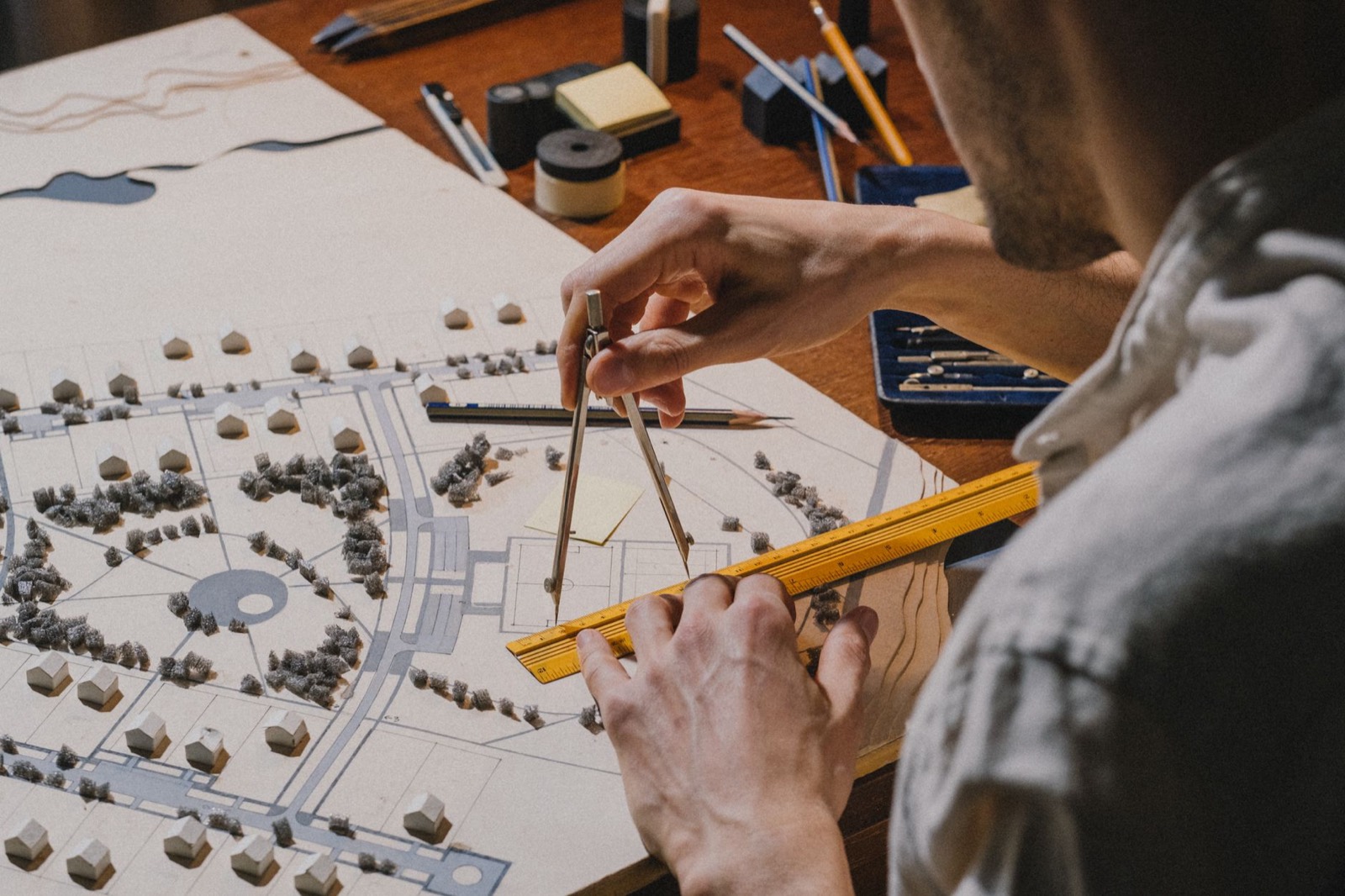 Hands measuring a white architectural model with a ruler