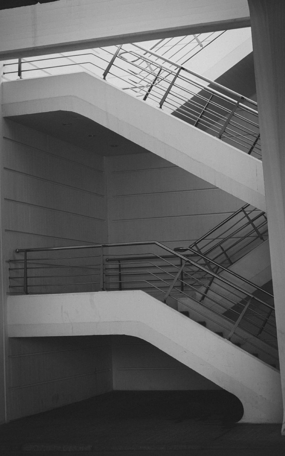 A white staircase with a steel rail, photographed in grey