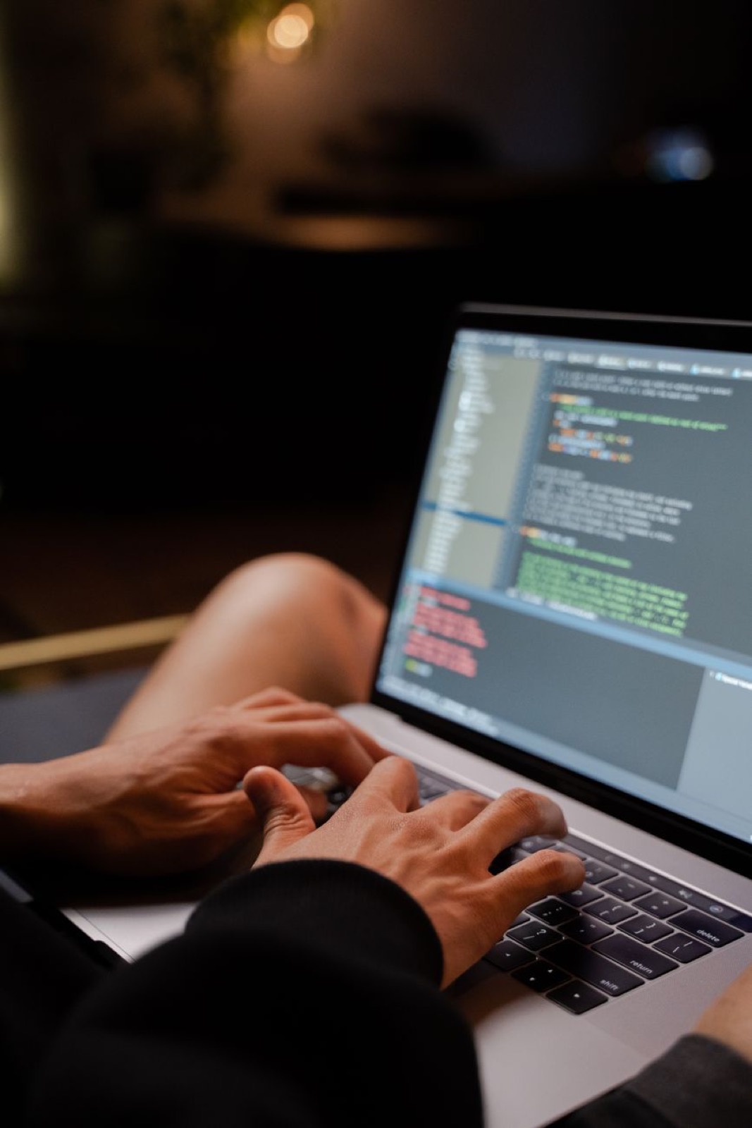 Hands typing on a laptop with code on screen