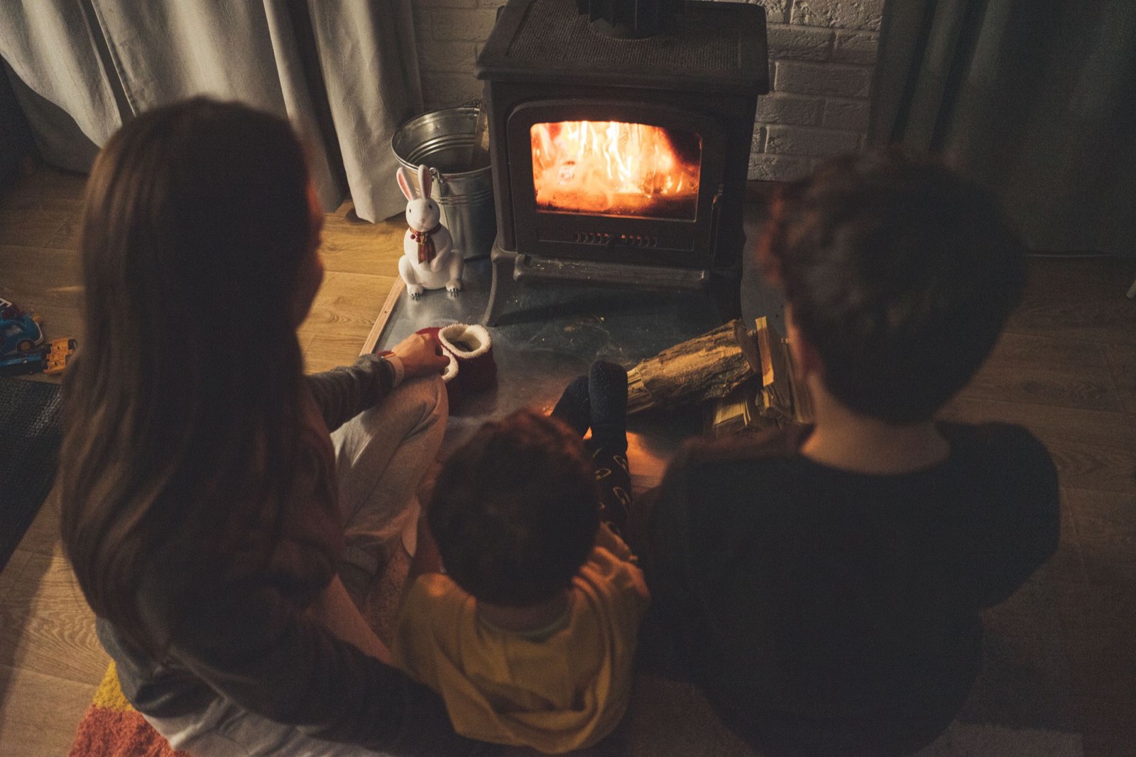 A family sitting by a wood stove in a warm living room