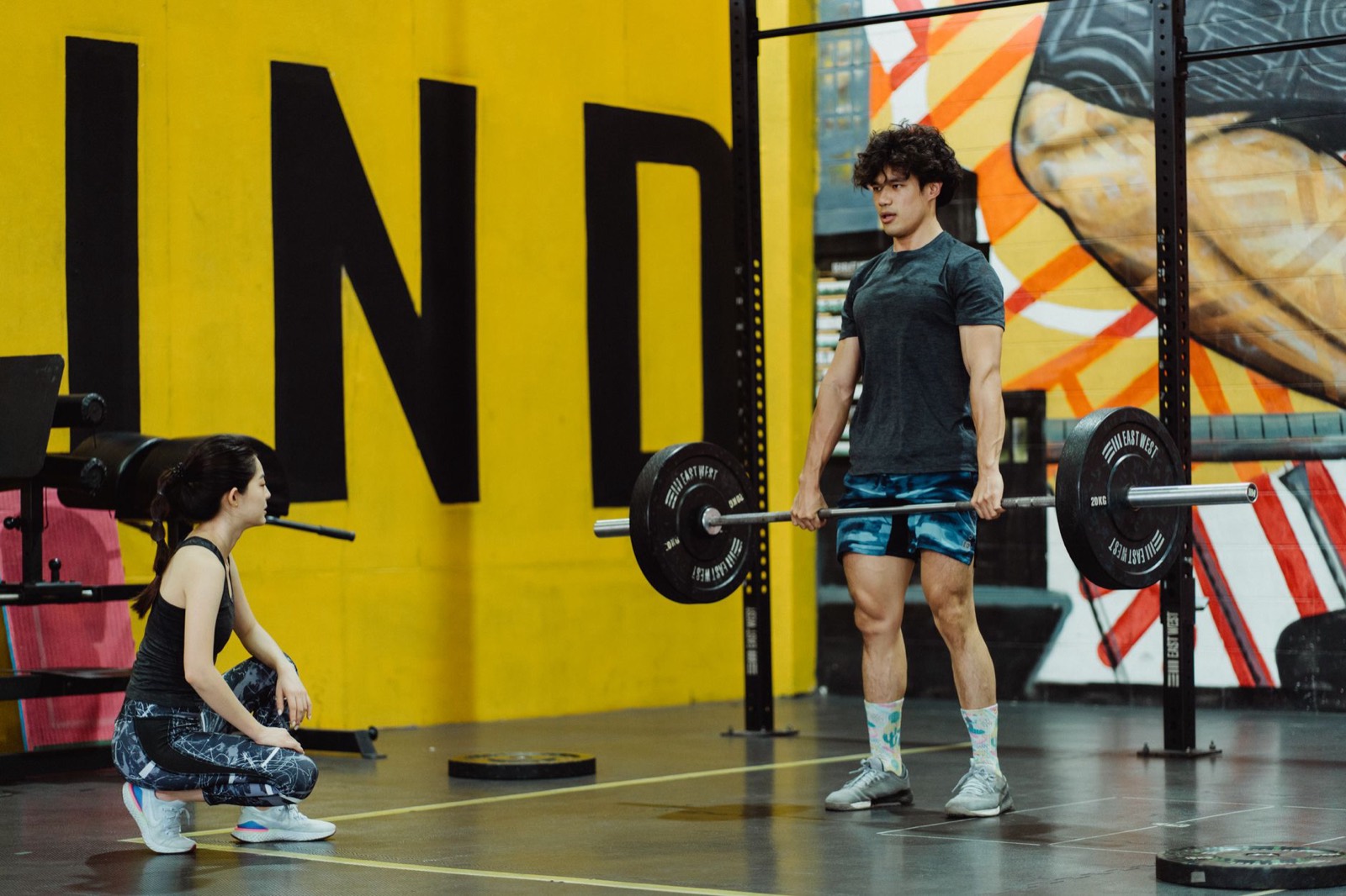 A lifter setting up a deadlift in front of a yellow wall