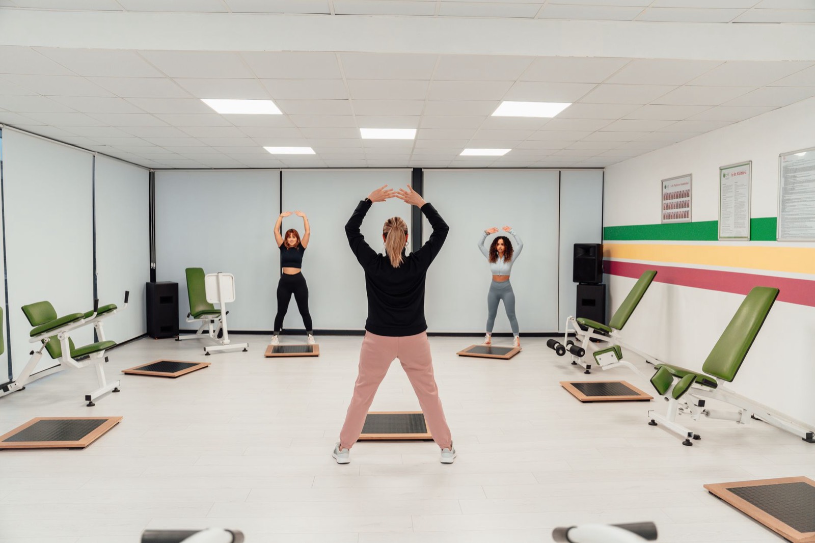 A bright studio class, arms raised, week one