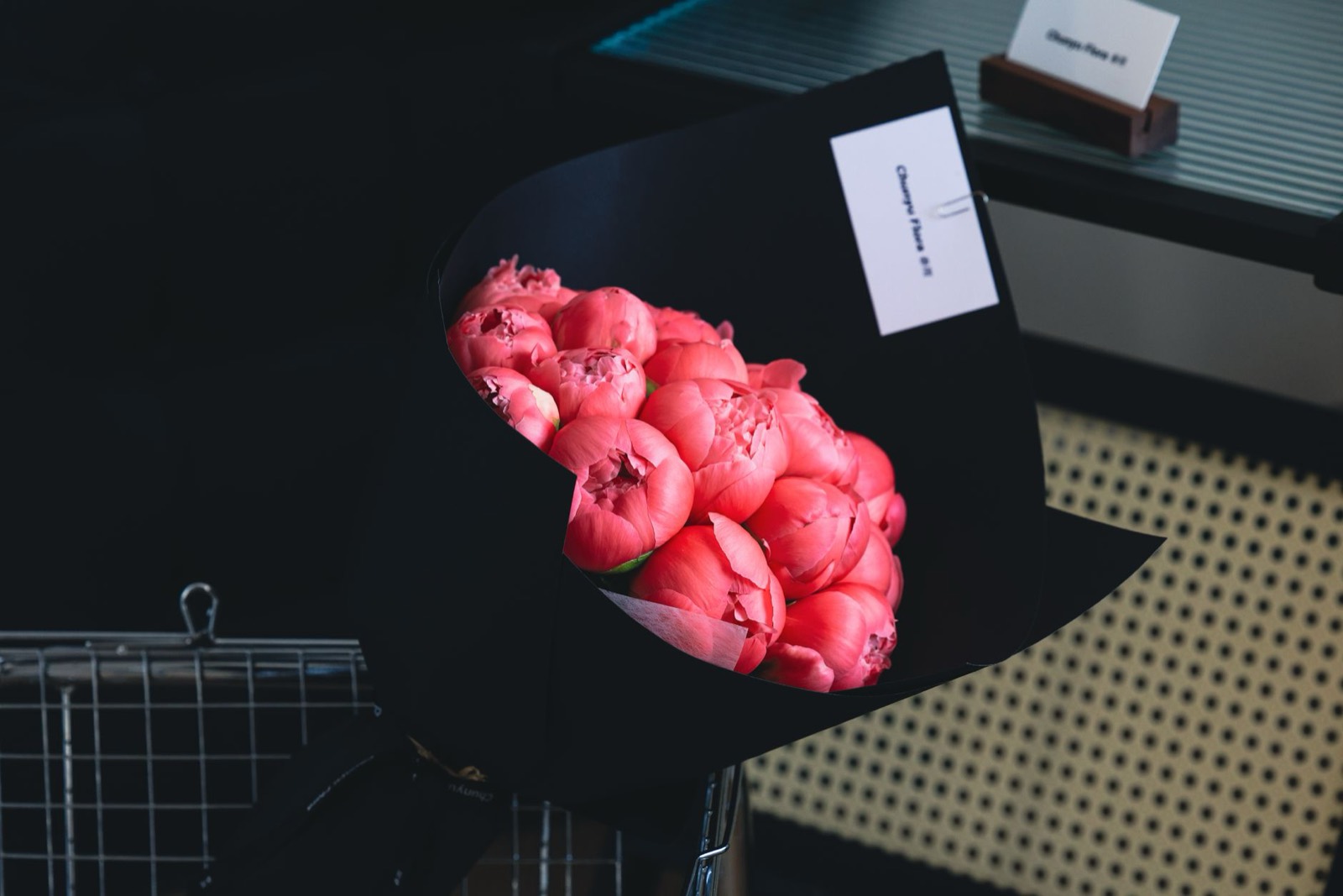 A bunch of coral peonies laid on a black studio table