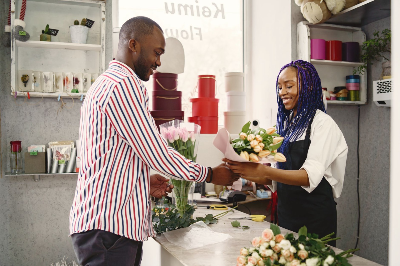 A florist handing a wrapped bouquet across the counter