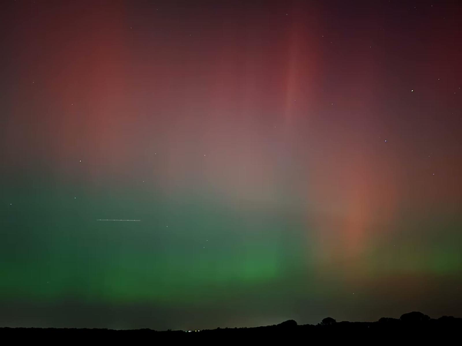 Green and red aurora over a dark horizon