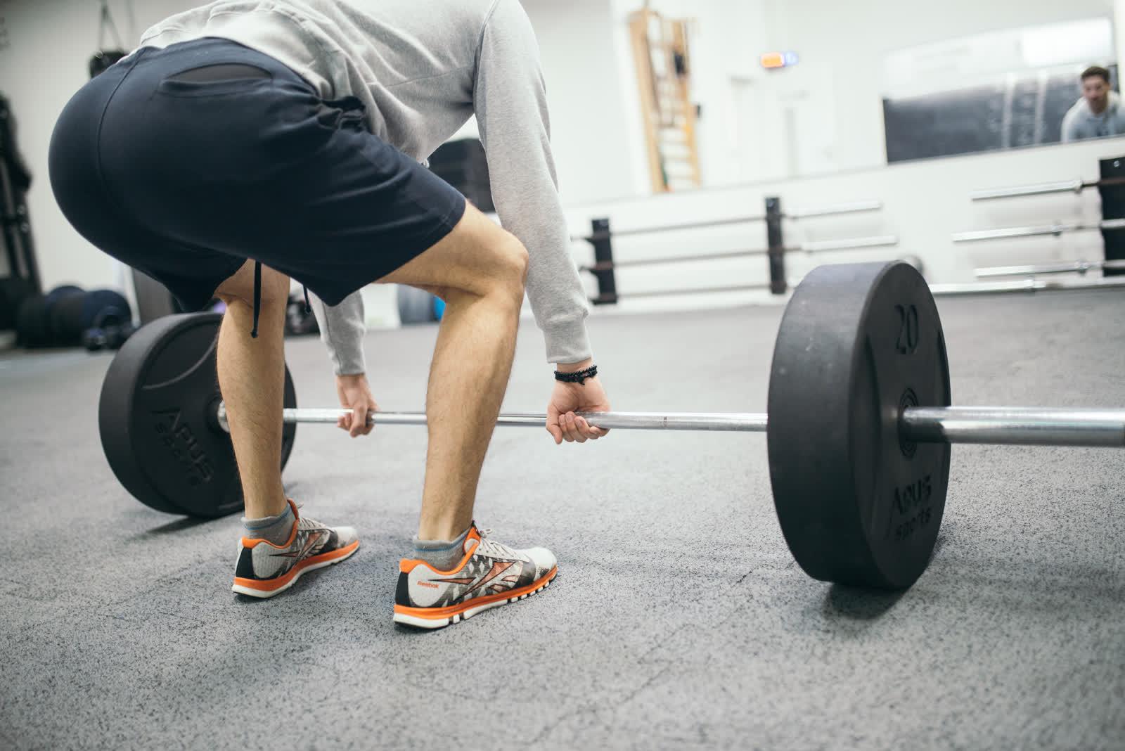 An athlete gripping a loaded barbell before a deadlift