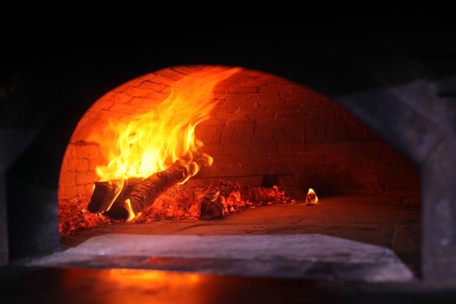 Flames rising inside Hearth & Vine's brick wood oven